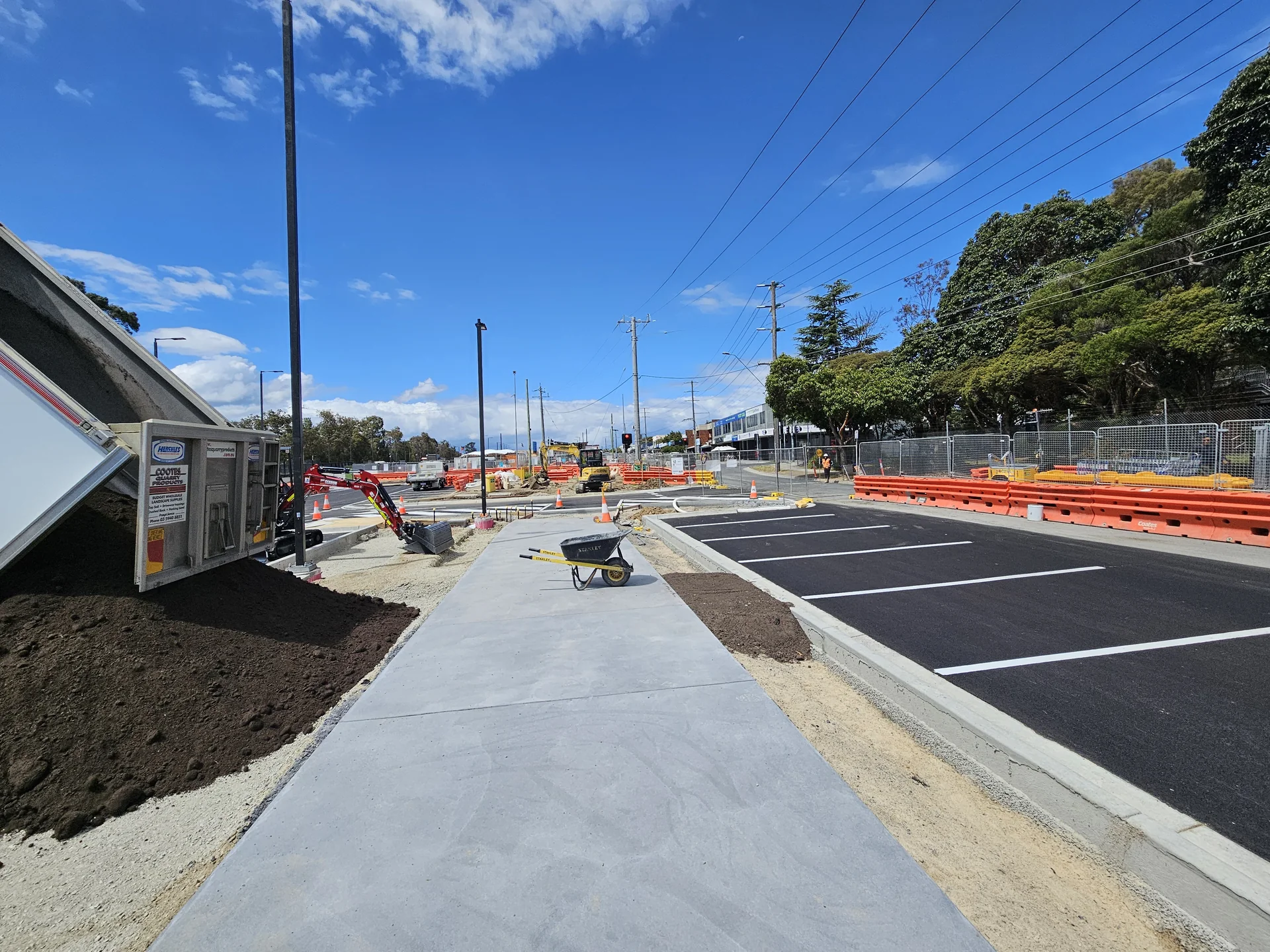 Prepared garden beds and landscape finishing beside paths and a car park at Ringwood East Station.