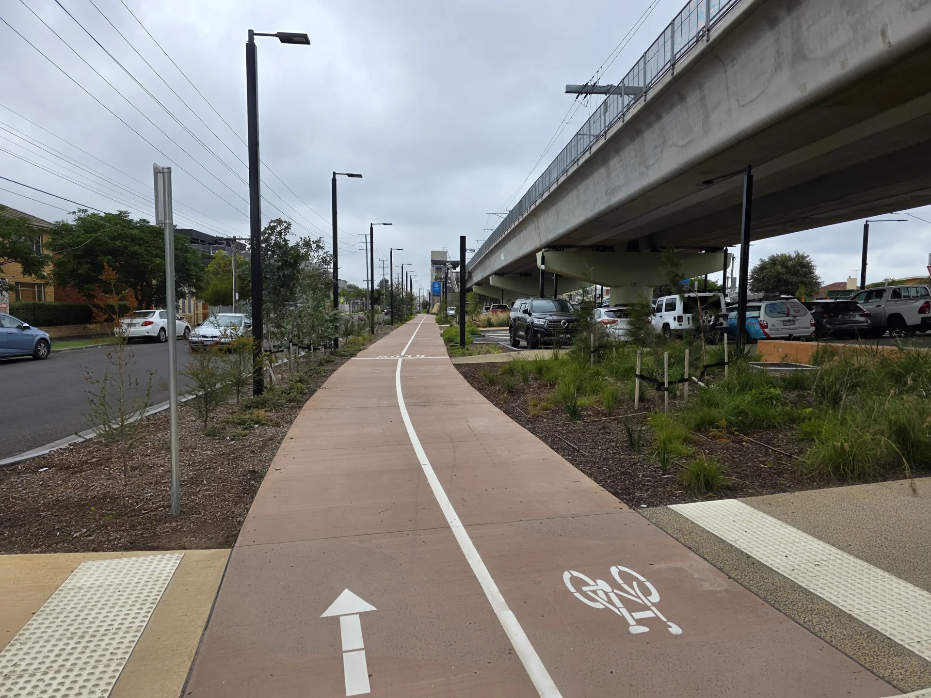 Completed shared-user path with line marking and tactile indicators beside transport infrastructure.